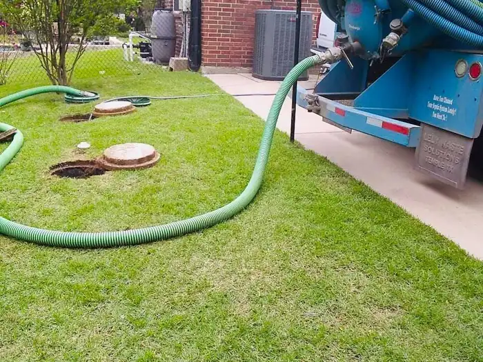 A residential septic pump-out in progress with the hose run to the tank lids