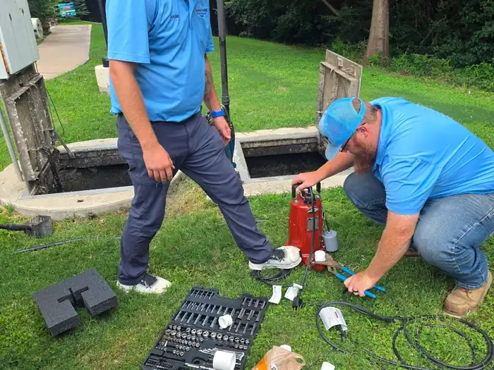 Two Burleson Septic technicians servicing a septic system at ground level